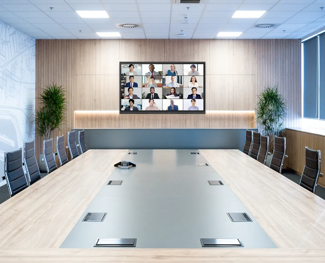 多人数参加のオンライン会議が映し出された大型ディスプレイが設置された会議室。