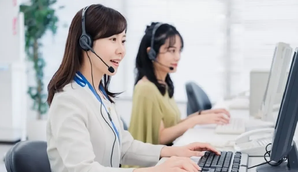 コールセンターでヘッドセットを付けた女性オペレーターがパソコンで対応中の様子